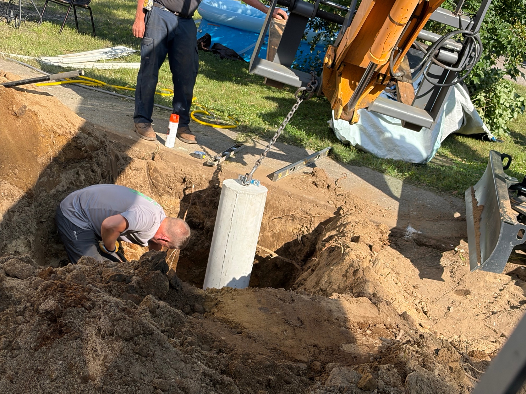 Nate's Septic crew setting a deck support, leveled with a chain off the mini excavator